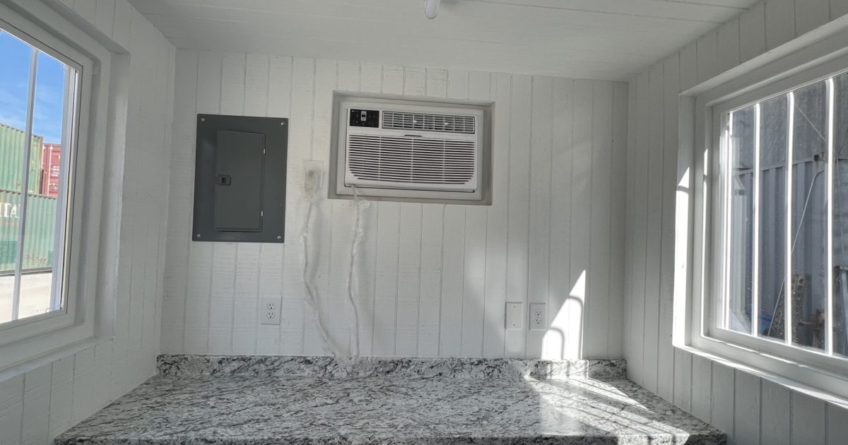 AC and electrical panel over desk in shipping container modification