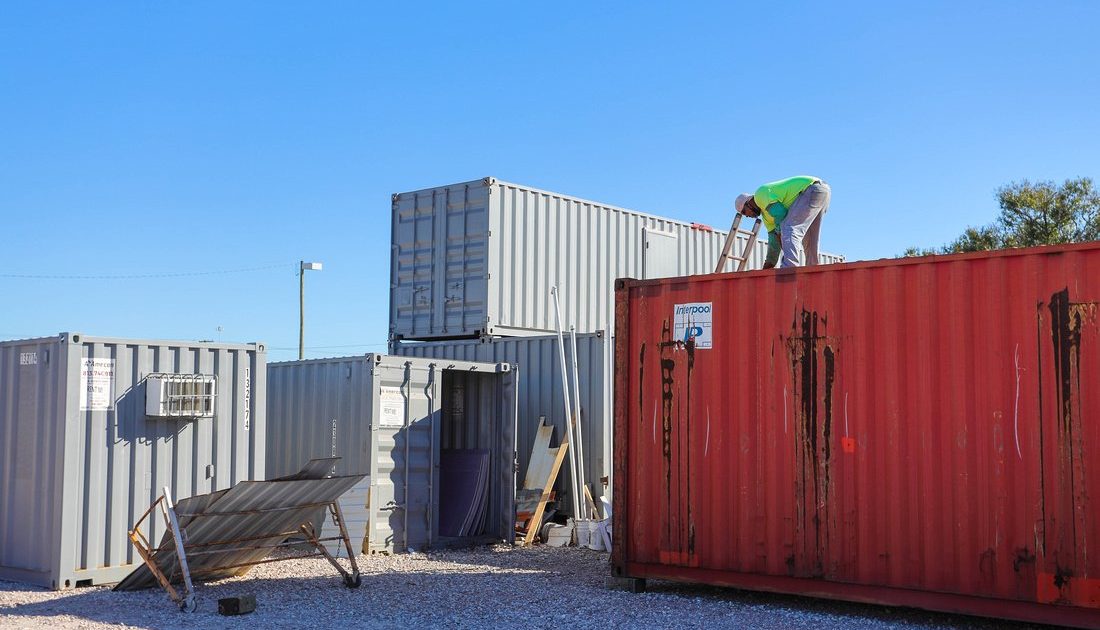 Modification team member on top of red shipping container